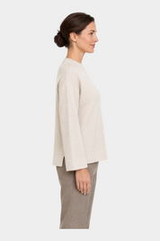 Modella indossa maglia girocollo Follower SRL color avorio con vestibilità boxy e spacchi laterali, vista laterale