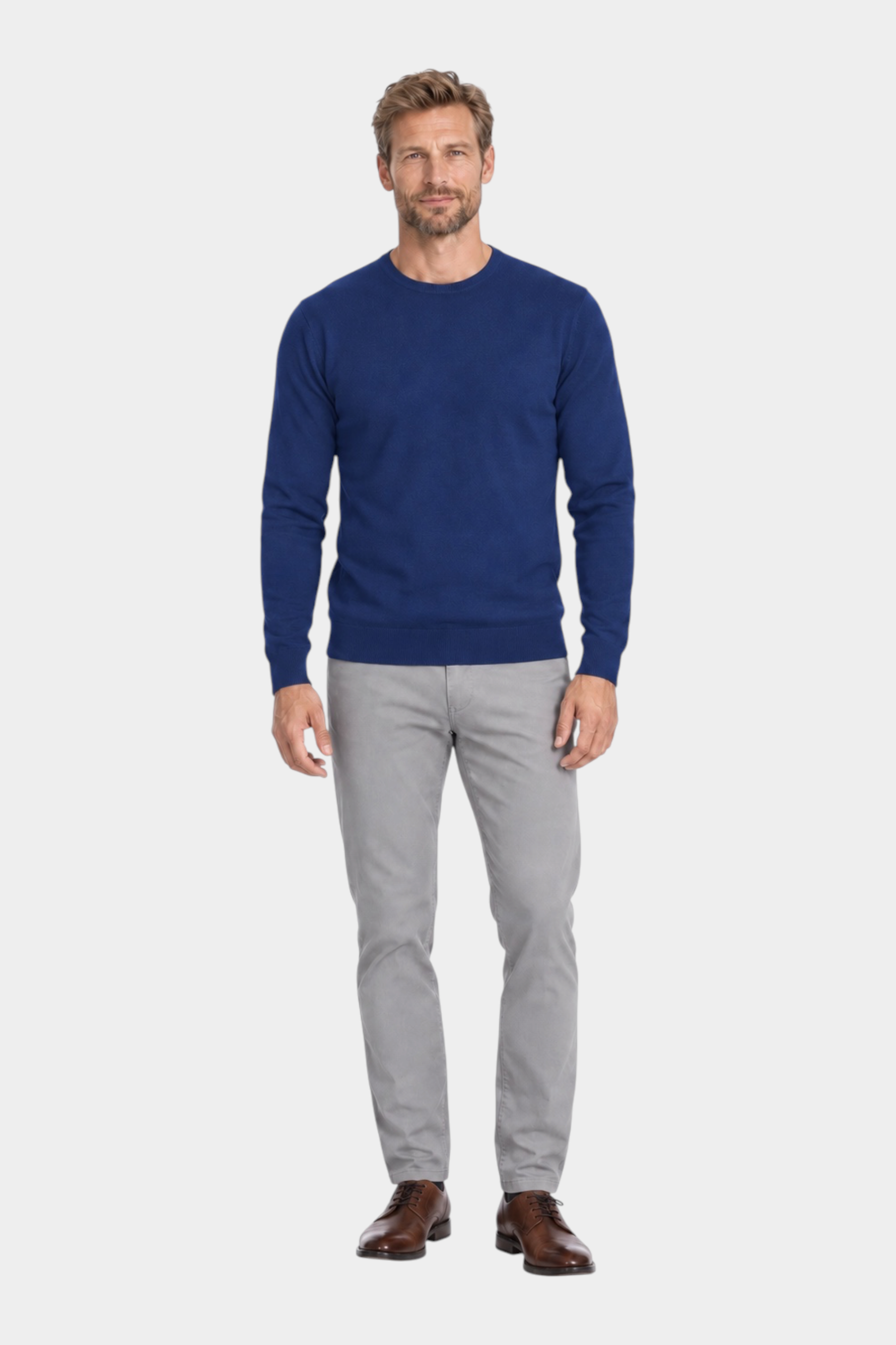 Modello indossa maglia girocollo blu in filo Ragno abbinata a pantaloni grigi, proposta da Follower SRL