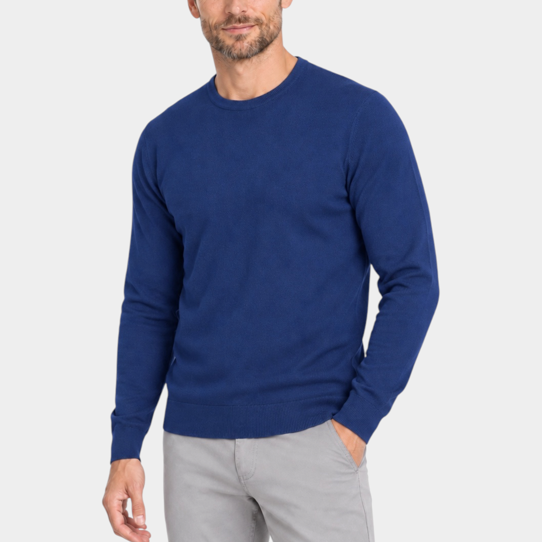 Modello indossa maglia girocollo blu in filo Ragno proposta da Follower SRL con pantaloni grigi su sfondo bianco