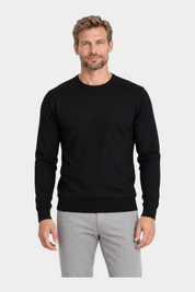 Modello indossa maglia girocollo nera in filo Ragno di Follower SRL con pantaloni grigi su sfondo bianco