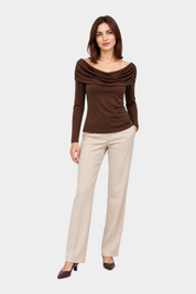 Modella indossa maglia marrone Follower SRL con scollo a barca drappeggiato e maniche lunghe, abbinata a pantaloni beige