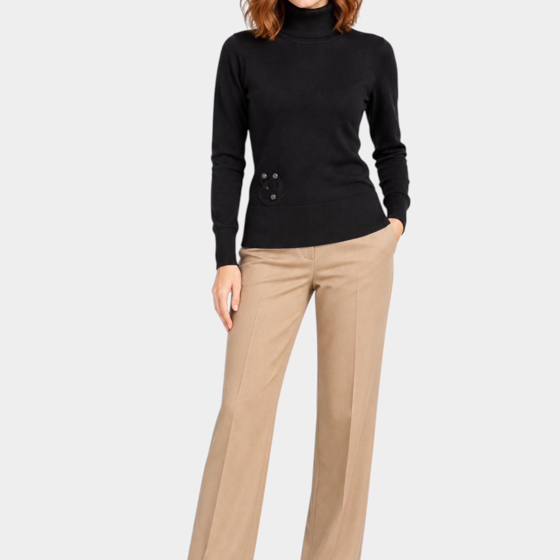 Modella indossa maglia a collo alto nera Follower SRL con dettaglio floreale laterale e pantaloni beige eleganti