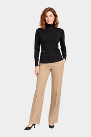 Modella indossa maglia a collo alto nera Follower SRL con dettaglio floreale laterale e pantaloni beige eleganti