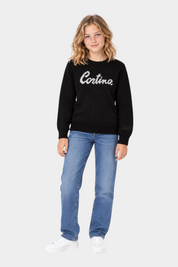 Ragazza indossa maglia girocollo nera Follower SRL con scritta Cortina in strass, abbinata a jeans e sneakers bianche