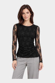 Modella indossa maglia nera Follower SRL in pizzo ricamato a maniche lunghe con dettaglio drappeggiato sul fianco