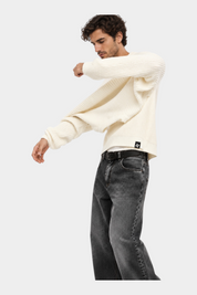 Modello indossa maglione girocollo Follower SRL beige a maglia larga con vestibilità regular e jeans grigi