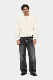 Maglione girocollo Follower SRL beige a maglia larga indossato da un modello con jeans grigi