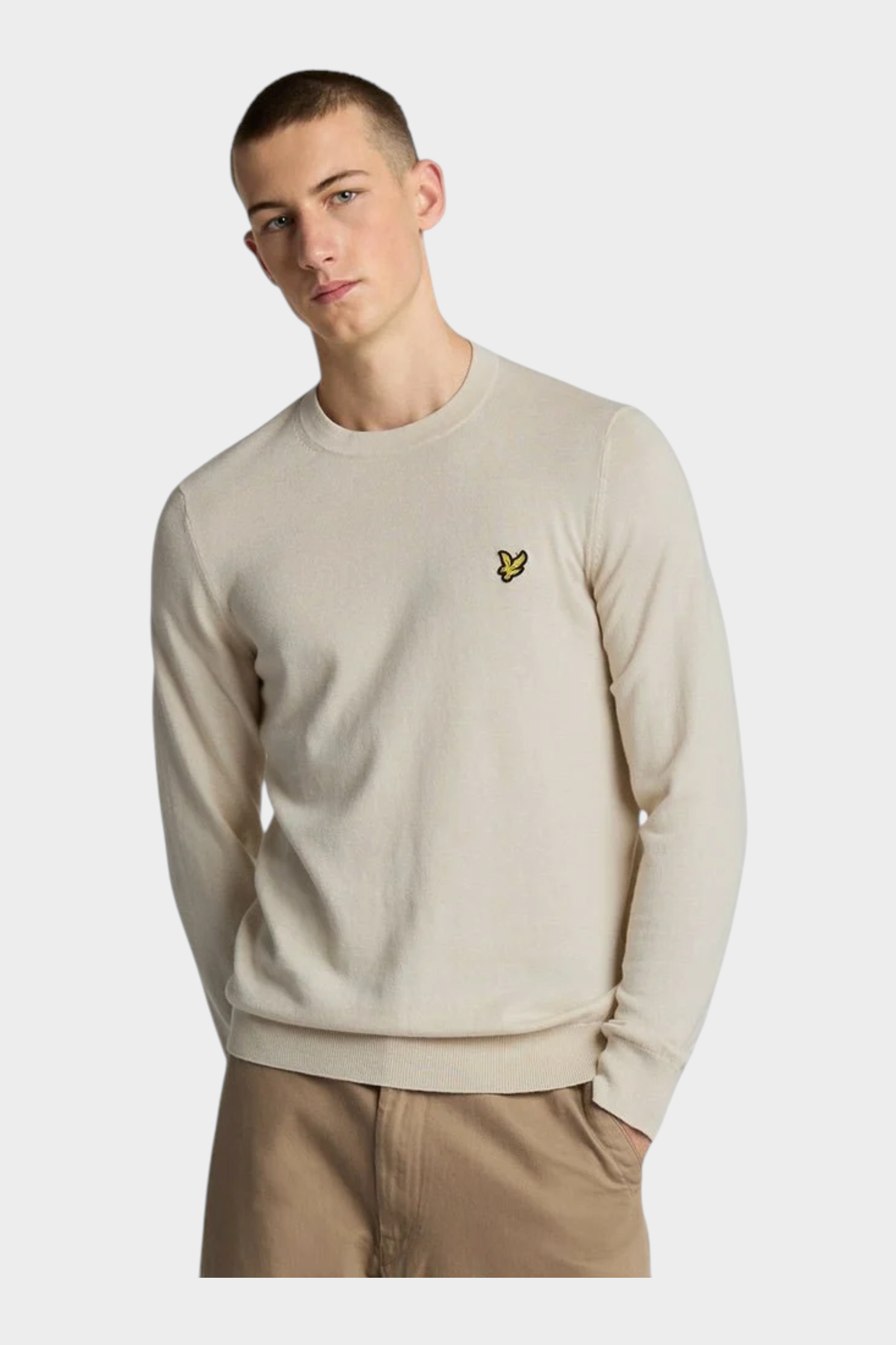 Modello indossa maglione girocollo beige in cotone e lana merino Follower SRL con logo ricamato sul petto