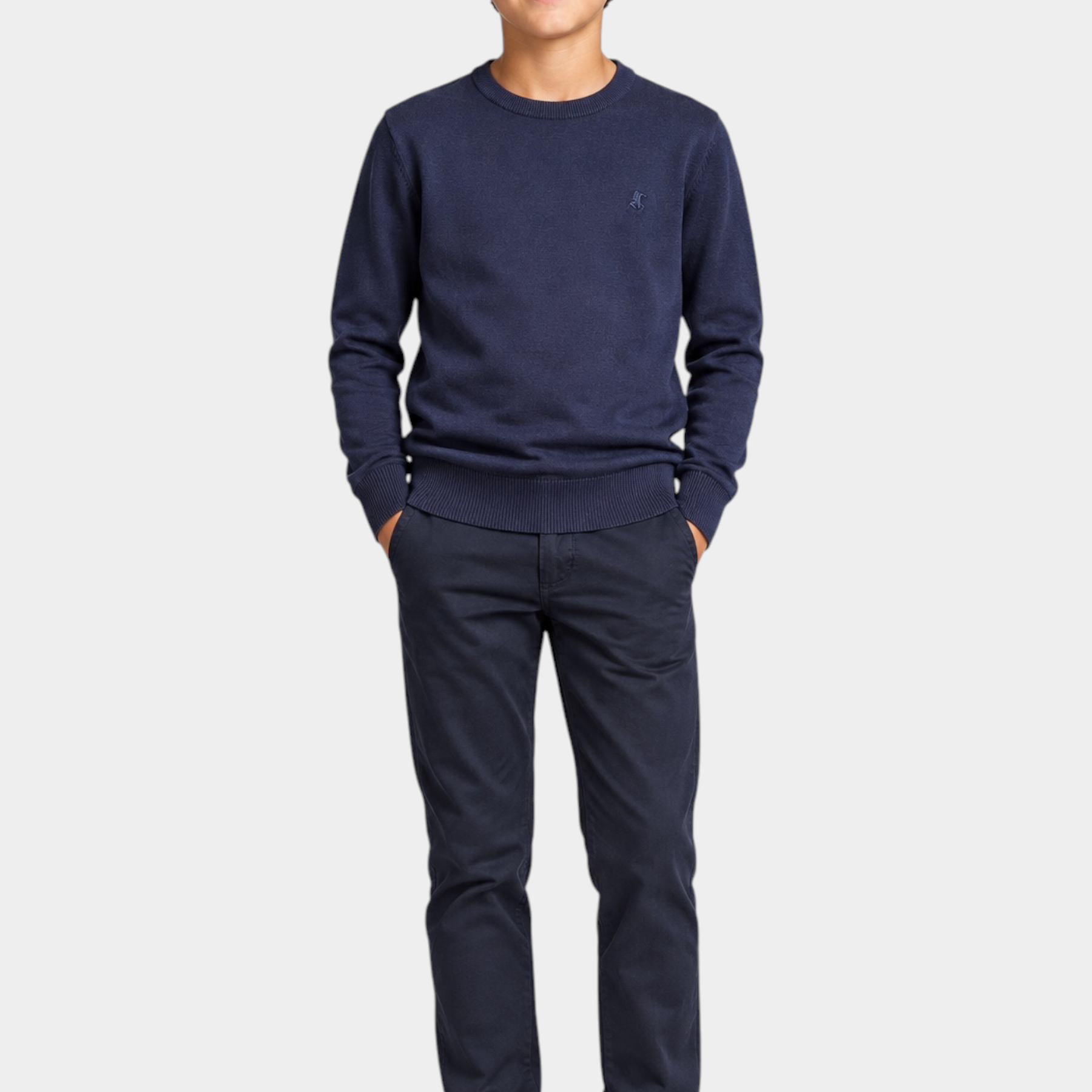 Ragazzo indossa maglione girocollo blu Follower SRL con logo iconico, pantaloni scuri e sneakers bianche