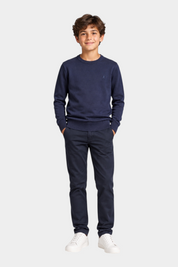 Ragazzo indossa maglione girocollo blu Follower SRL con logo iconico, pantaloni scuri e sneakers bianche