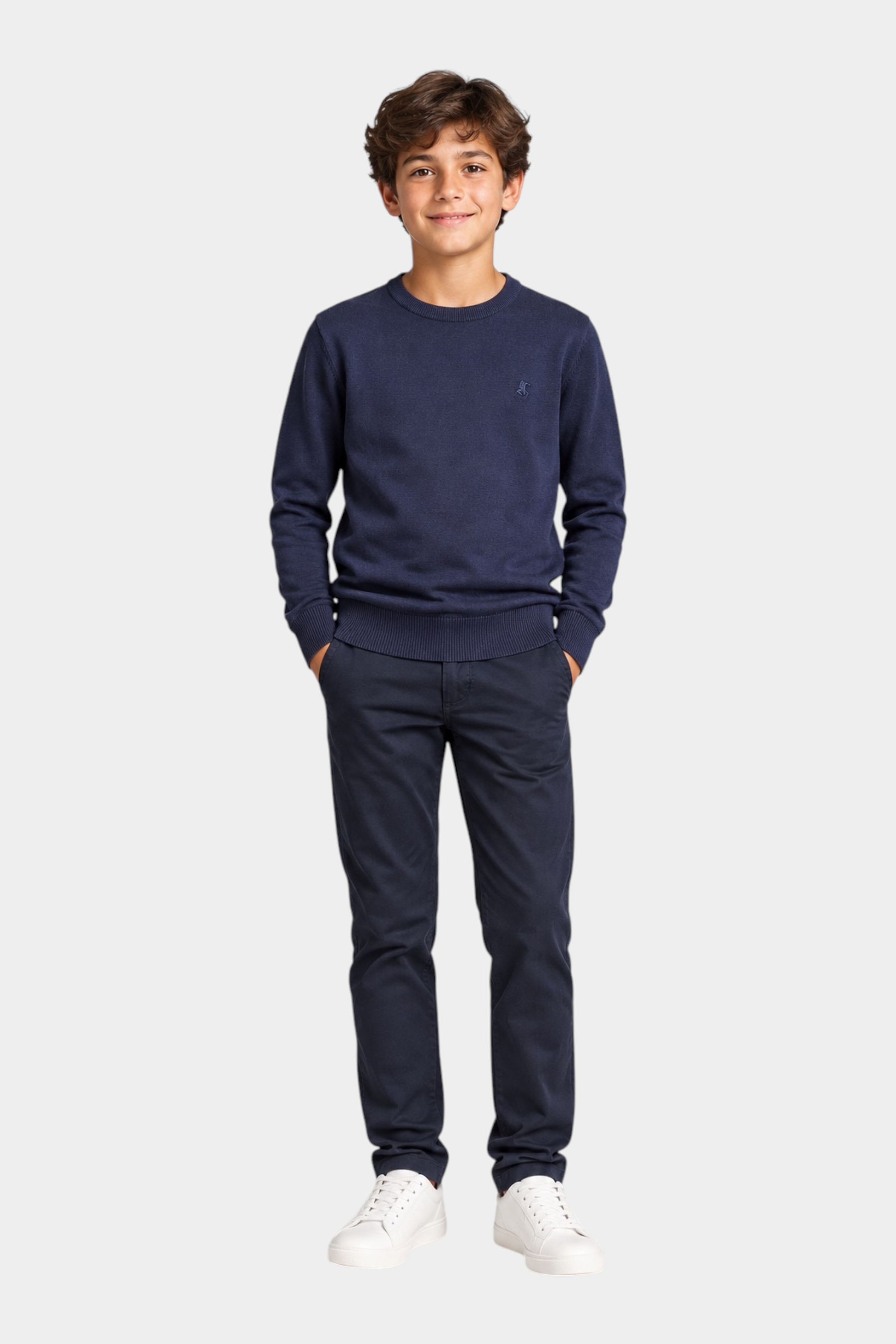 Ragazzo indossa maglione girocollo blu Follower SRL con logo iconico, pantaloni scuri e sneakers bianche
