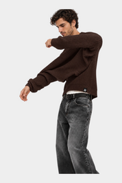 Modello indossa maglione girocollo marrone a maglia larga Follower SRL con jeans grigi su sfondo bianco