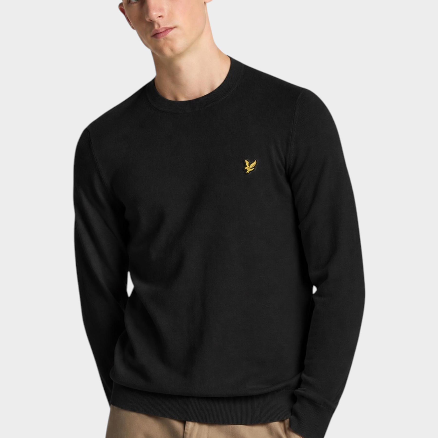 Modello indossa maglione girocollo nero in cotone e lana merino Follower SRL con logo dorato sul petto