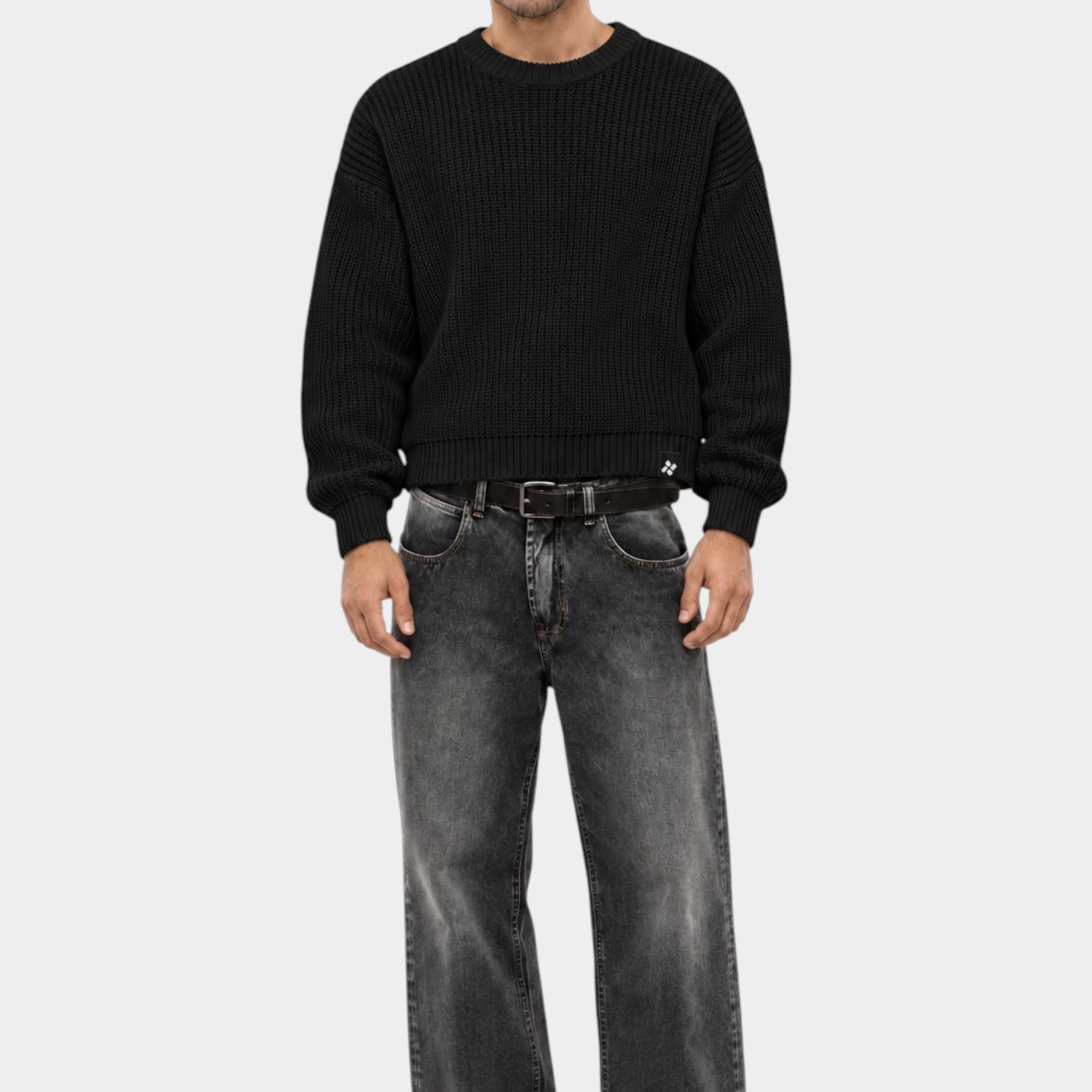 Modello indossa maglione girocollo nero a maglia larga Follower SRL con jeans grigi dal taglio ampio