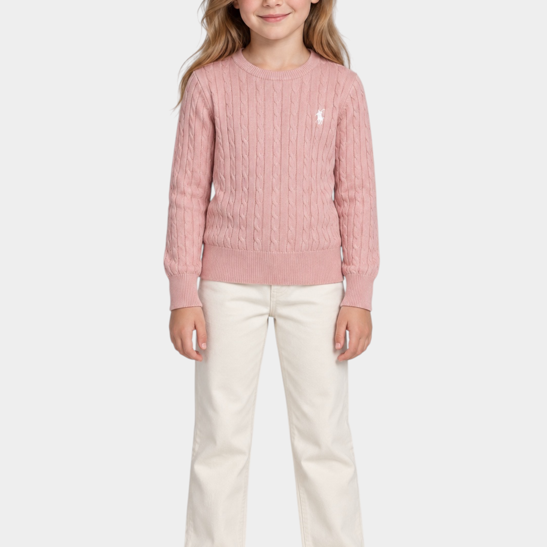 Bambina indossa un maglione a treccia rosa Follower SRL con logo ricamato, abbinato a pantaloni chiari e sneakers.