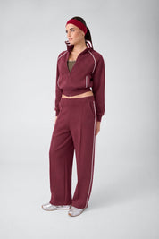 Modella indossa pantalone jogger bordeaux GUESS con banda laterale bianca, parte di una tuta Follower SRL