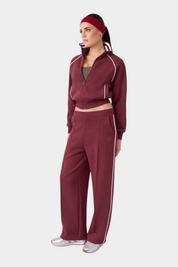 Modella indossa pantalone jogger bordeaux GUESS con banda laterale bianca, parte di una tuta Follower SRL