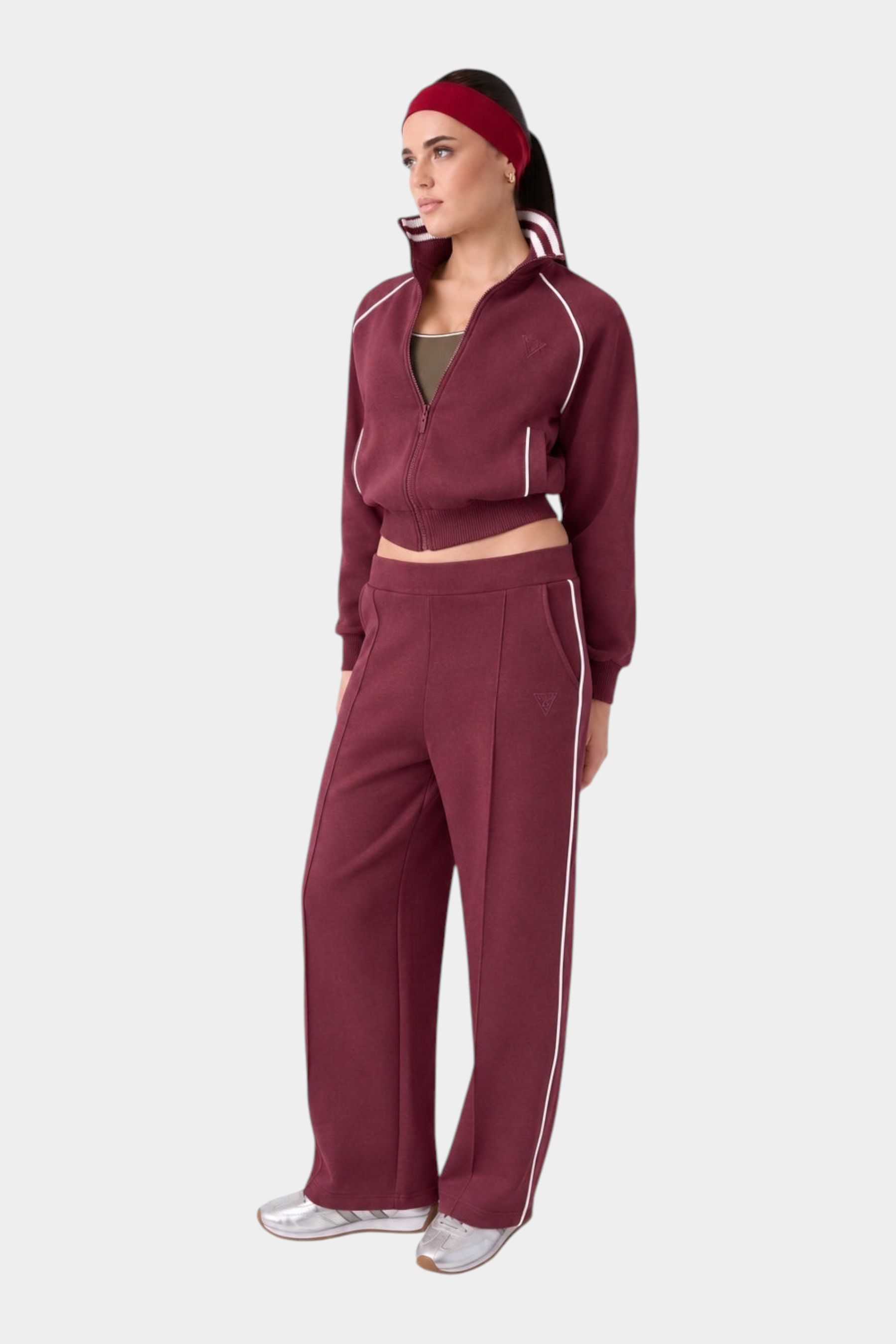 Modella indossa pantalone jogger bordeaux GUESS con banda laterale bianca, parte di una tuta Follower SRL