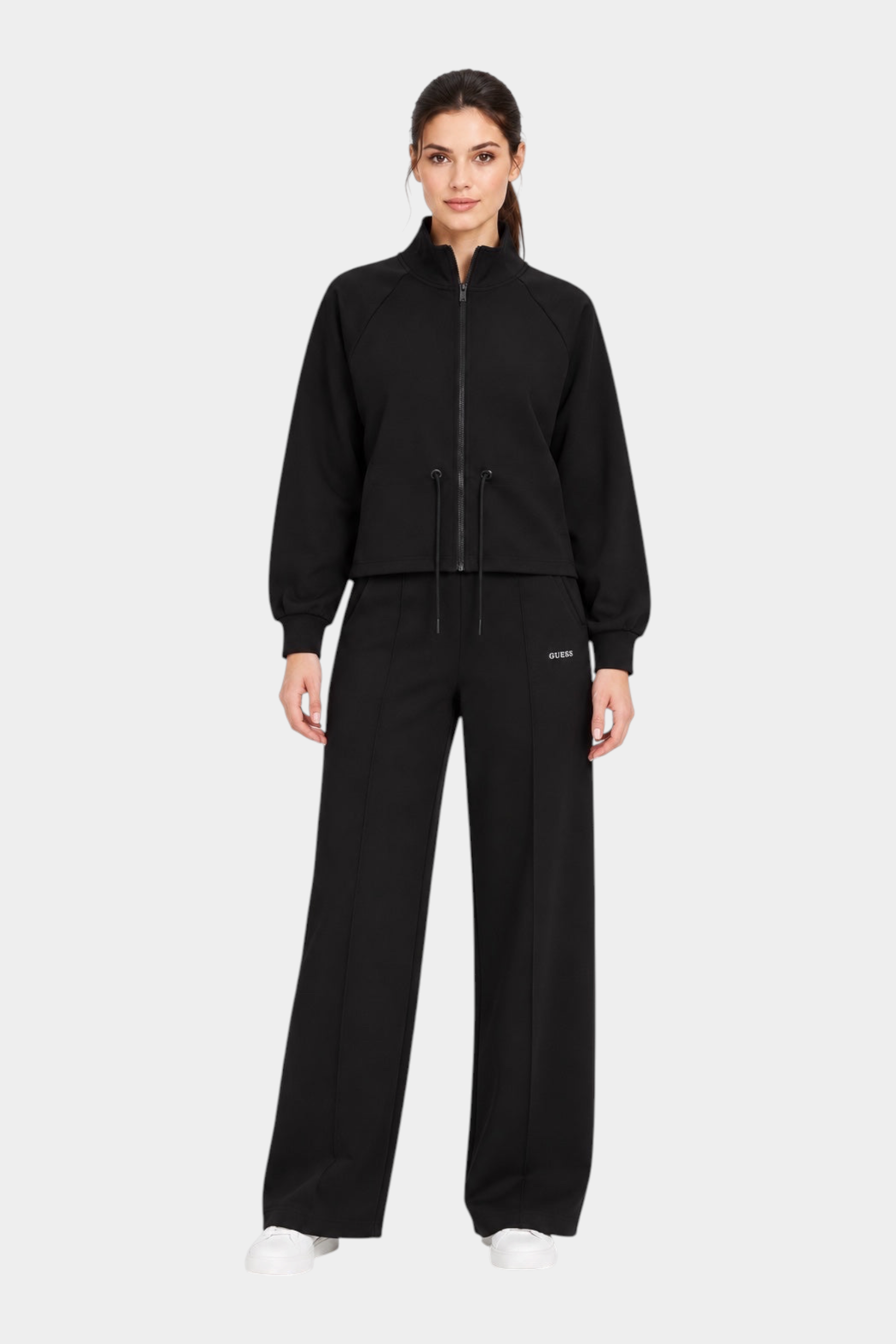 Modella indossa pantaloni jogger neri GUESS con felpa coordinata e scarpe da ginnastica bianche, Follower SRL