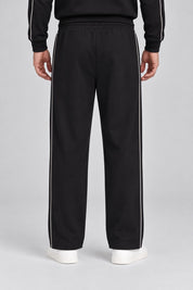 Pantalone jogger nero da uomo GUESS con bande laterali bianche a contrasto, visto da dietro su modello