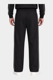 Pantalone jogger nero da uomo GUESS con bande laterali bianche a contrasto, visto da dietro su modello