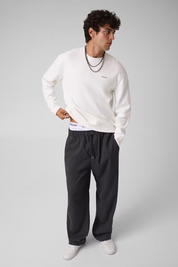 Modello indossa pantaloni a gamba larga grigi Follower SRL con vita elasticizzata e coulisse, abbinati a felpa bianca