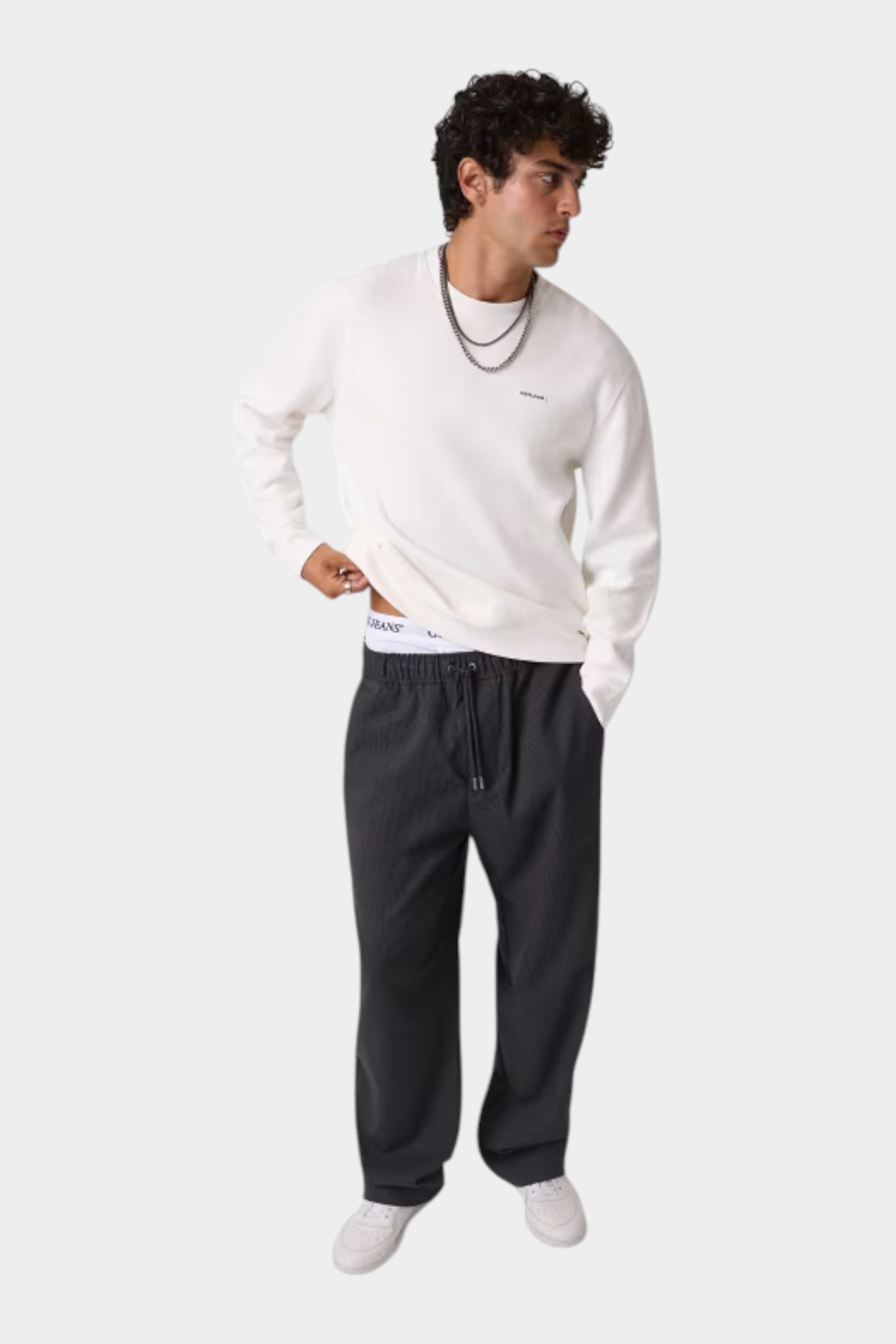 Modello indossa pantaloni a gamba larga grigi Follower SRL con vita elasticizzata e coulisse, abbinati a felpa bianca