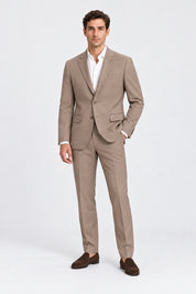 Modello indossa pantaloni classici beige GUESS di Follower SRL con giacca abbinata, camicia bianca e mocassini scuri.