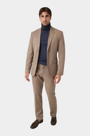 Modello indossa pantaloni classici beige GUESS con giacca abbinata e dolcevita blu scuro da Follower SRL