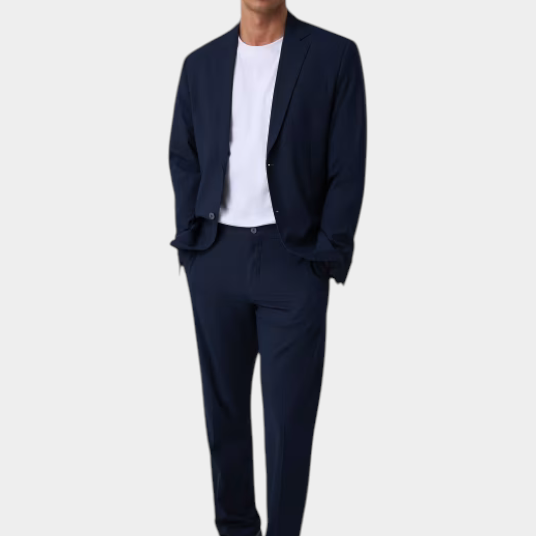 Modello indossa pantaloni classici blu GUESS con giacca abbinata e t-shirt bianca, collezione Follower SRL