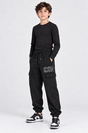 Ragazzo indossa pantaloni jogger cargo neri Follower SRL con scritta ICON bianca e tasche laterali