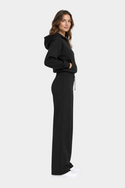 Modella indossa pantaloni jogger neri GUESS con felpa coordinata, vista laterale, collezione Follower SRL