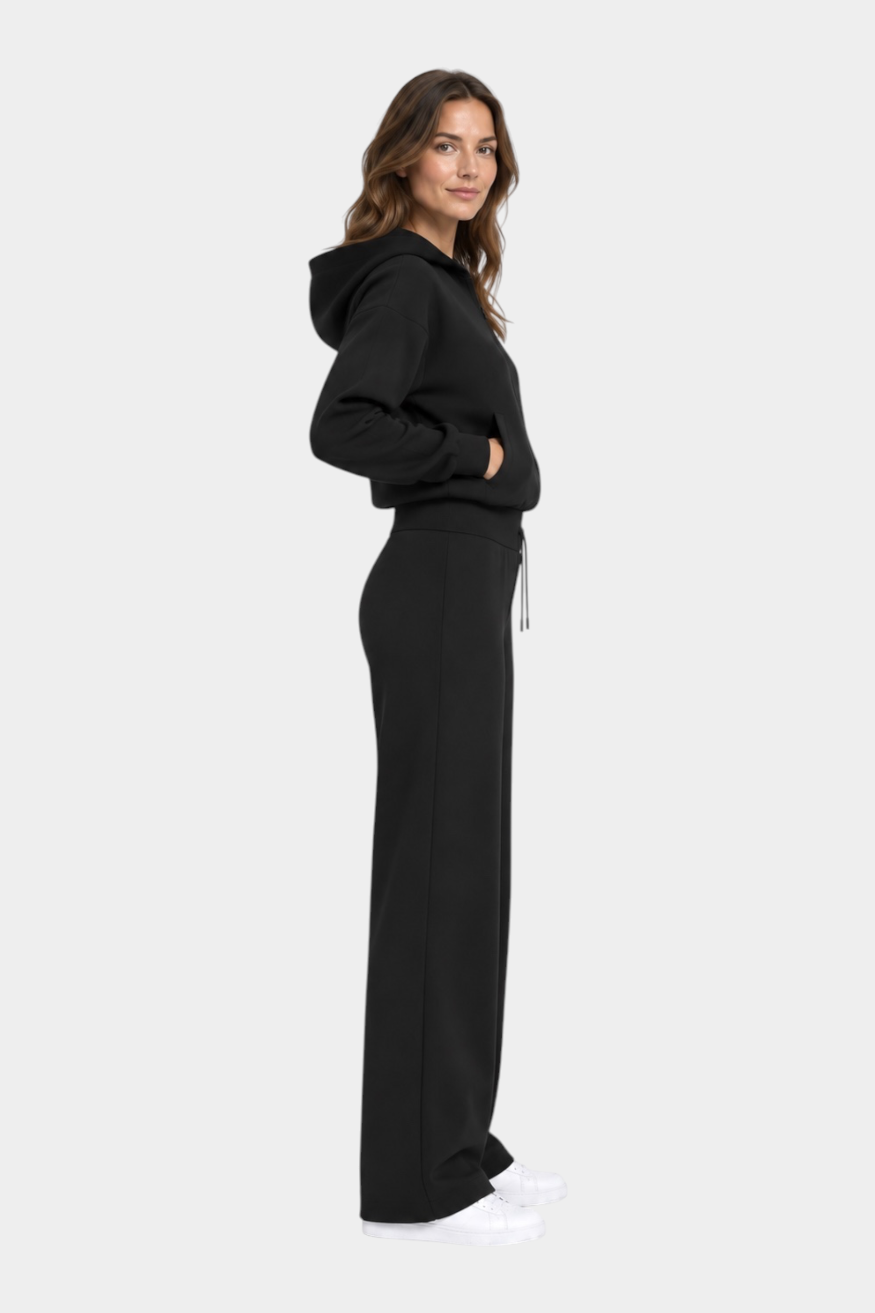 Modella indossa pantaloni jogger neri GUESS con felpa coordinata, vista laterale, collezione Follower SRL