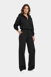 Modella indossa pantaloni jogger neri GUESS con logo 4G e felpa con zip abbinata, stile casual Follower SRL