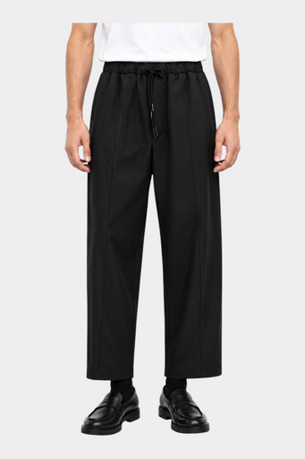 Pantaloni neri baggy-fit Follower SRL con coulisse in vita e pince frontali, indossati da un modello