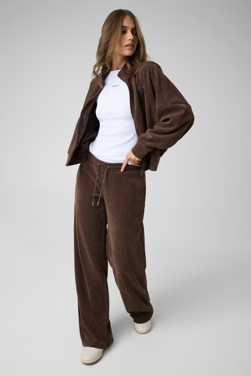 Modella indossa pantaloni della tuta a coste marroni GUESS con giacca abbinata, stile casual Follower SRL