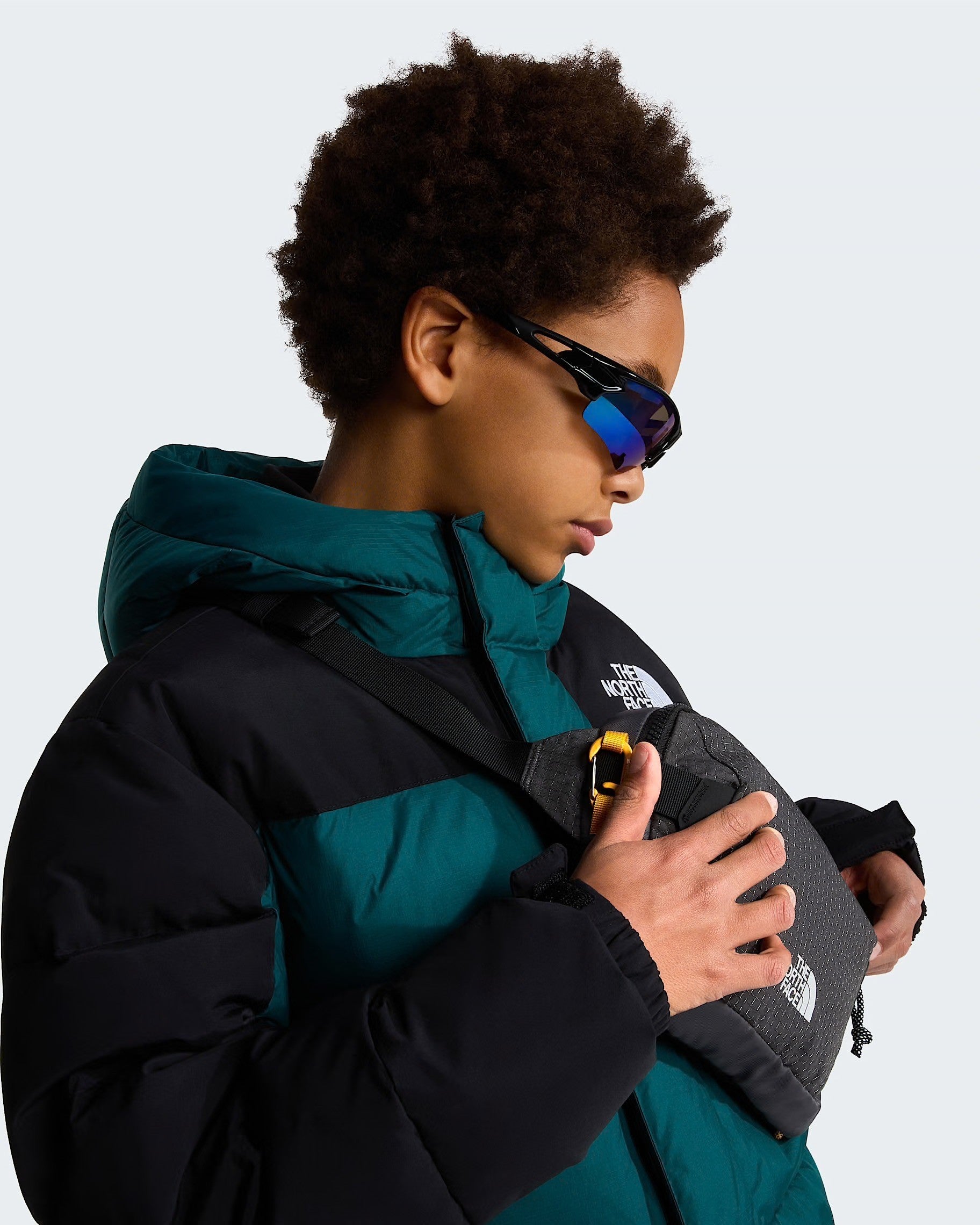 Ragazzo indossa parka corto imbottito verde e nero Follower SRL con marsupio e occhiali sportivi