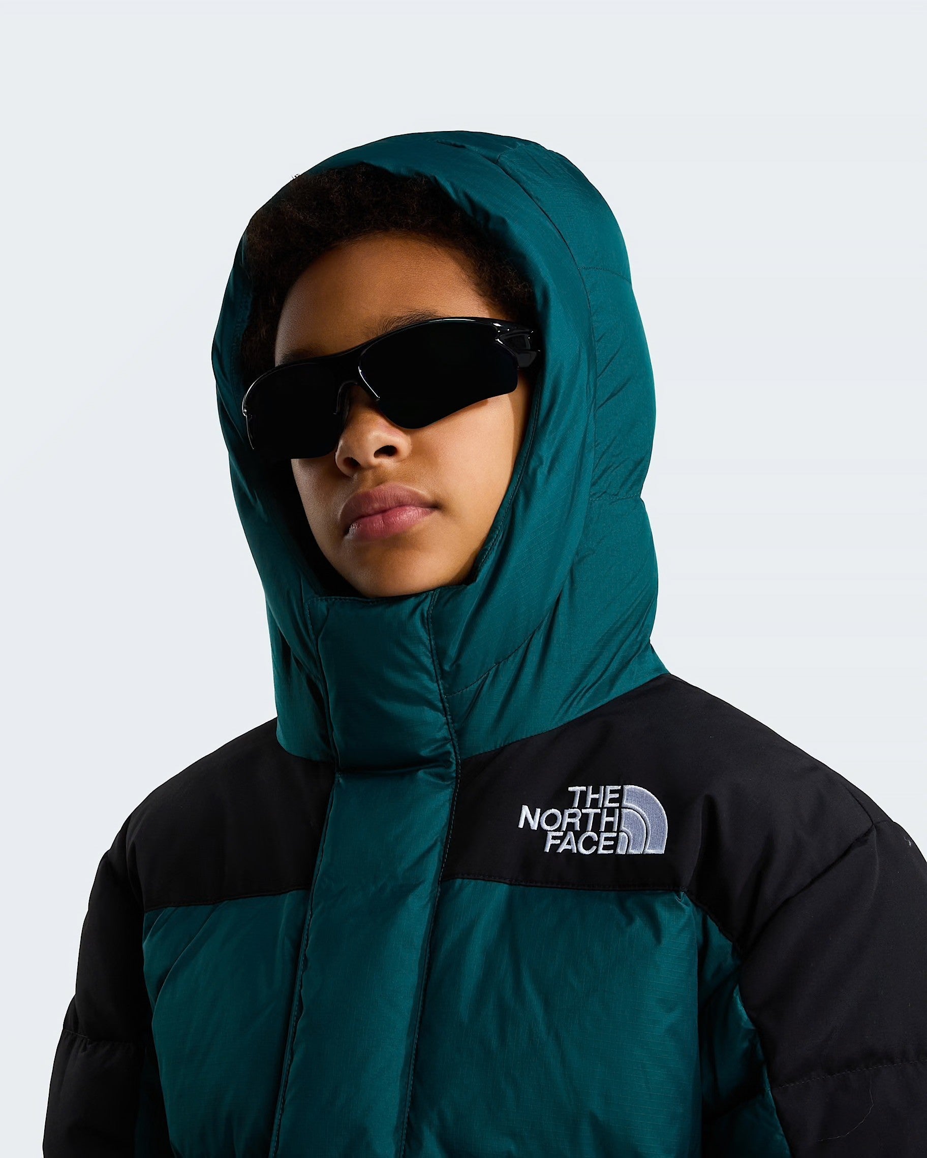 Modello con parka corto Follower SRL The North Face verde e nero con imbottitura in piumino e cappuccio indossato