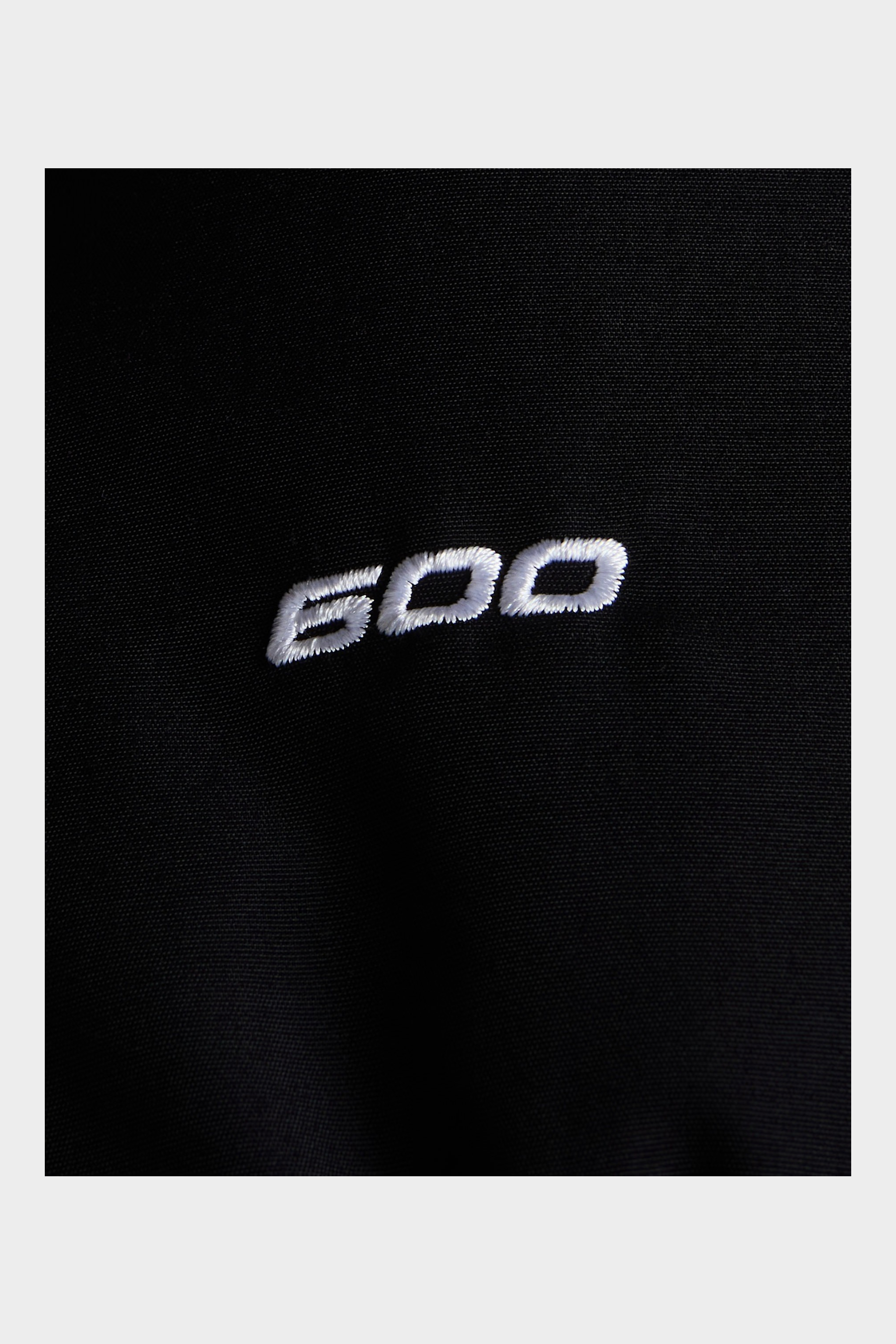 Dettaglio del ricamo bianco 600 su tessuto tecnico nero di un parka Follower SRL The North Face