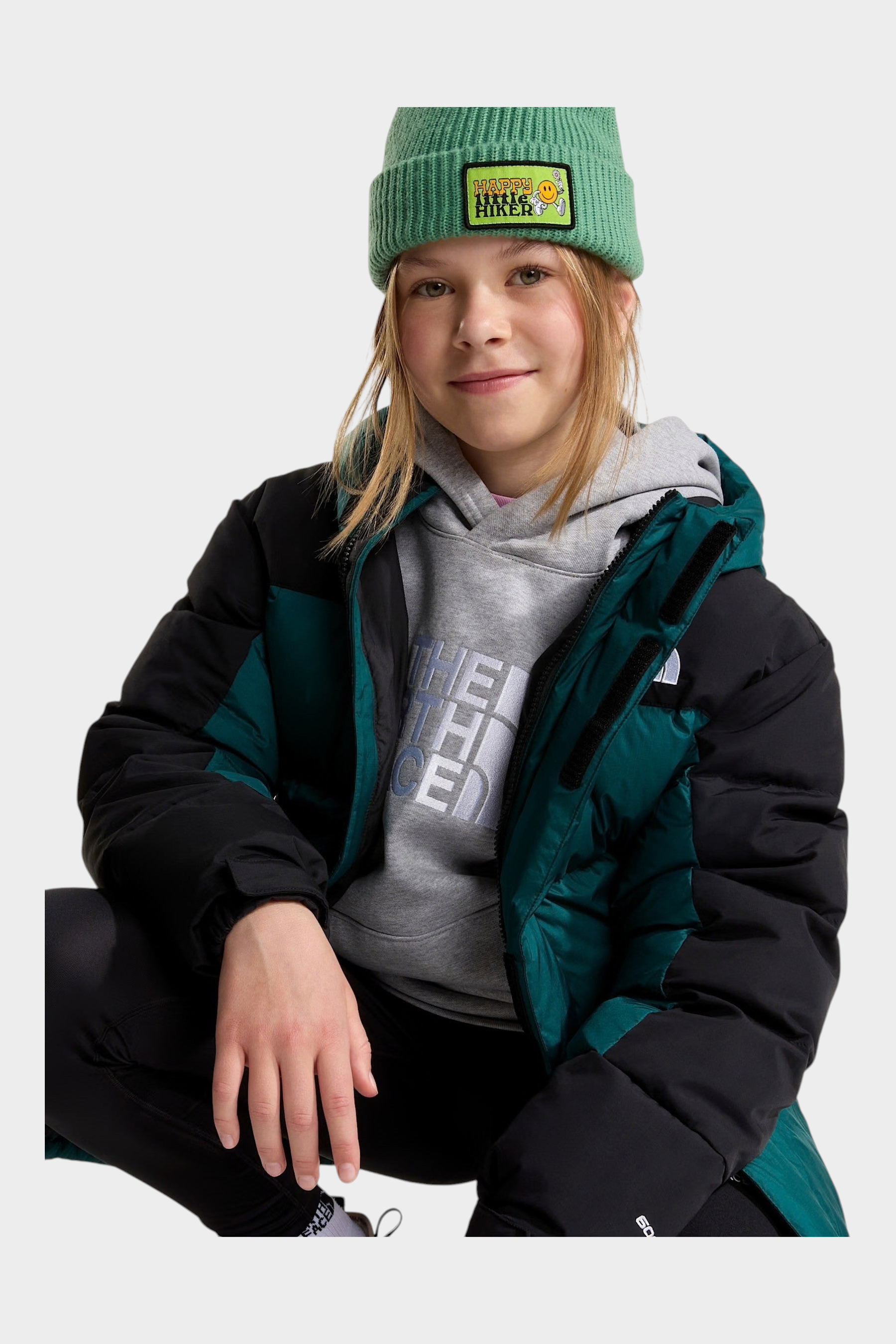 Ragazza indossa un parka corto Follower SRL The North Face verde e nero con imbottitura in piumino e berretto verde