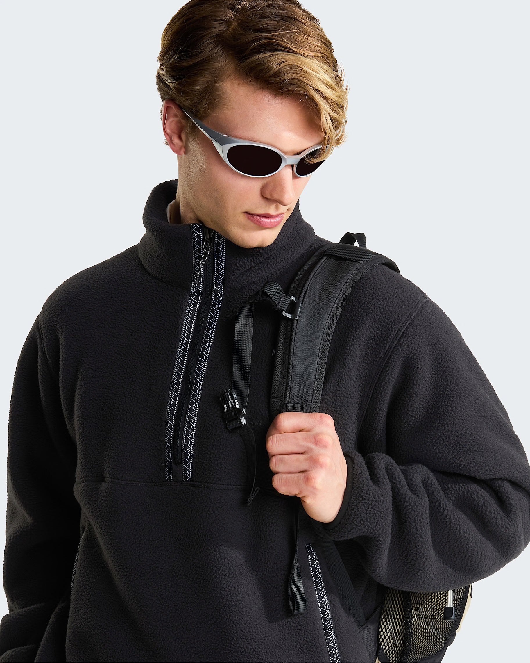 Modello indossa pile nero THE NORTH FACE con cerniera a 1/4 e zaino, proposto da Follower SRL