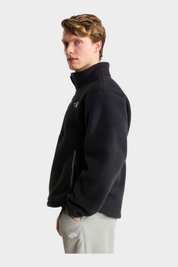 Modello indossa pile nero THE NORTH FACE Fleeski con cerniera a 1/4, vista laterale su sfondo neutro Follower SRL