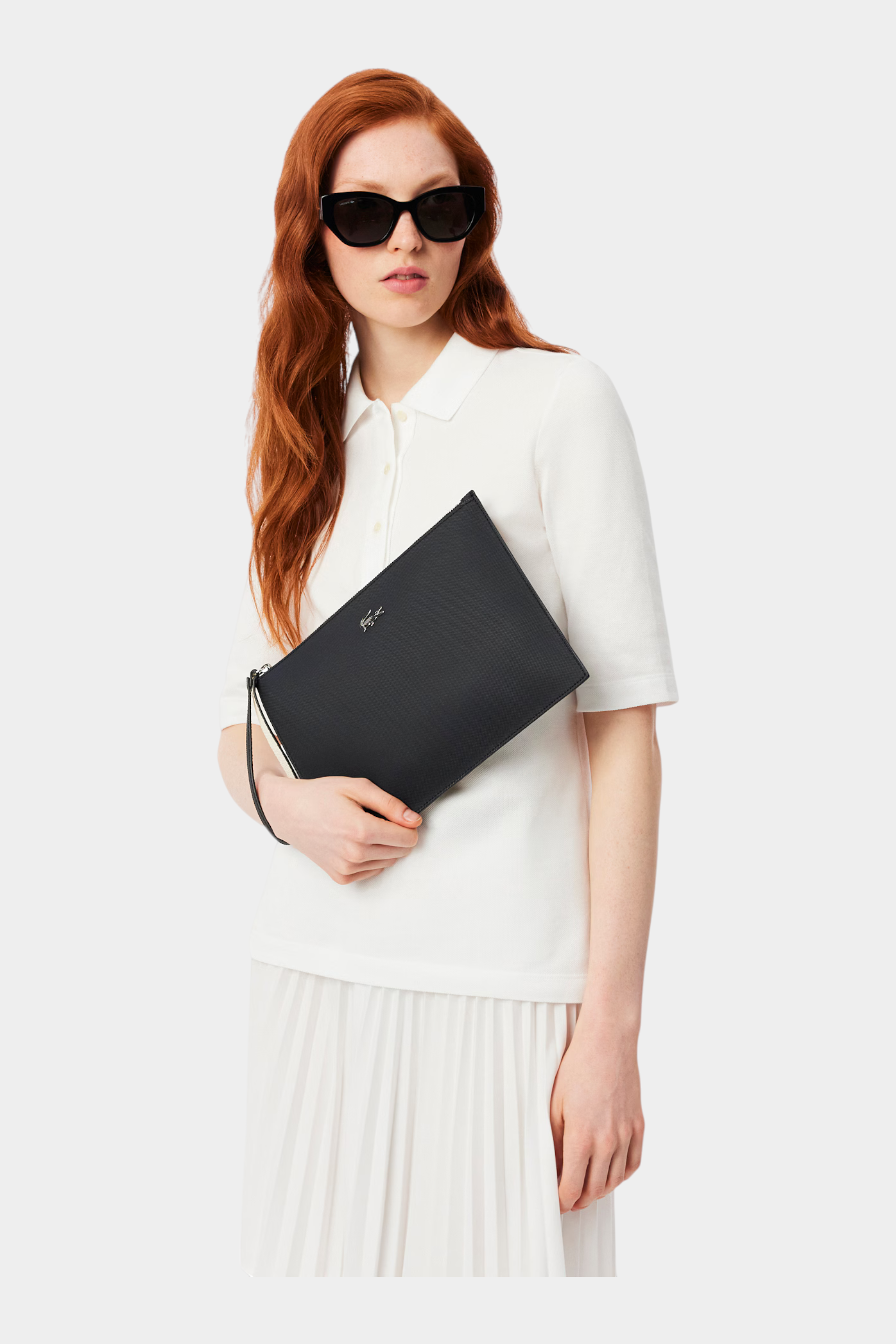Modella con occhiali da sole indossa una pochette nera in canvas piqué spalmato Follower SRL Lacoste