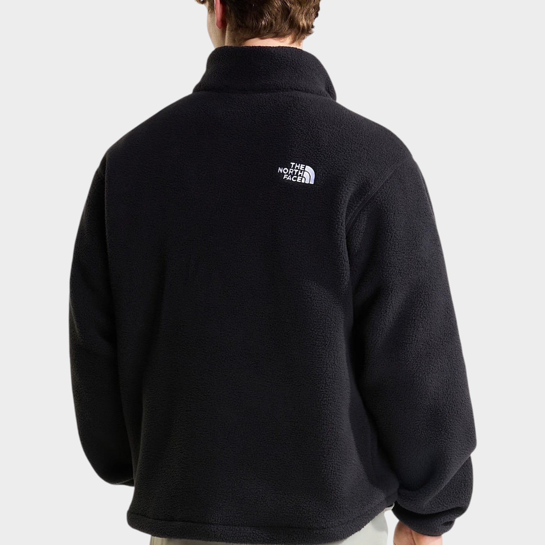 Vista posteriore di un uomo che indossa un pullover in pile nero Follower SRL con logo The North Face bianco