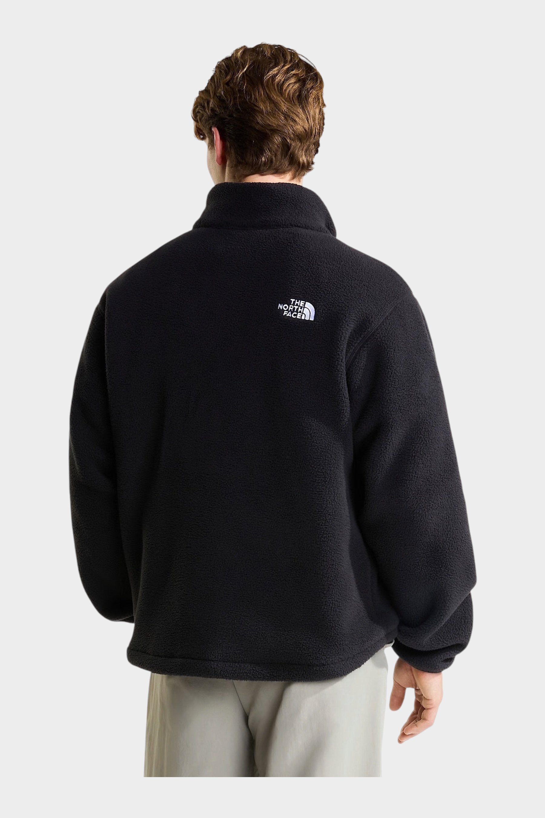 Vista posteriore di un uomo che indossa un pullover in pile nero Follower SRL con logo The North Face bianco
