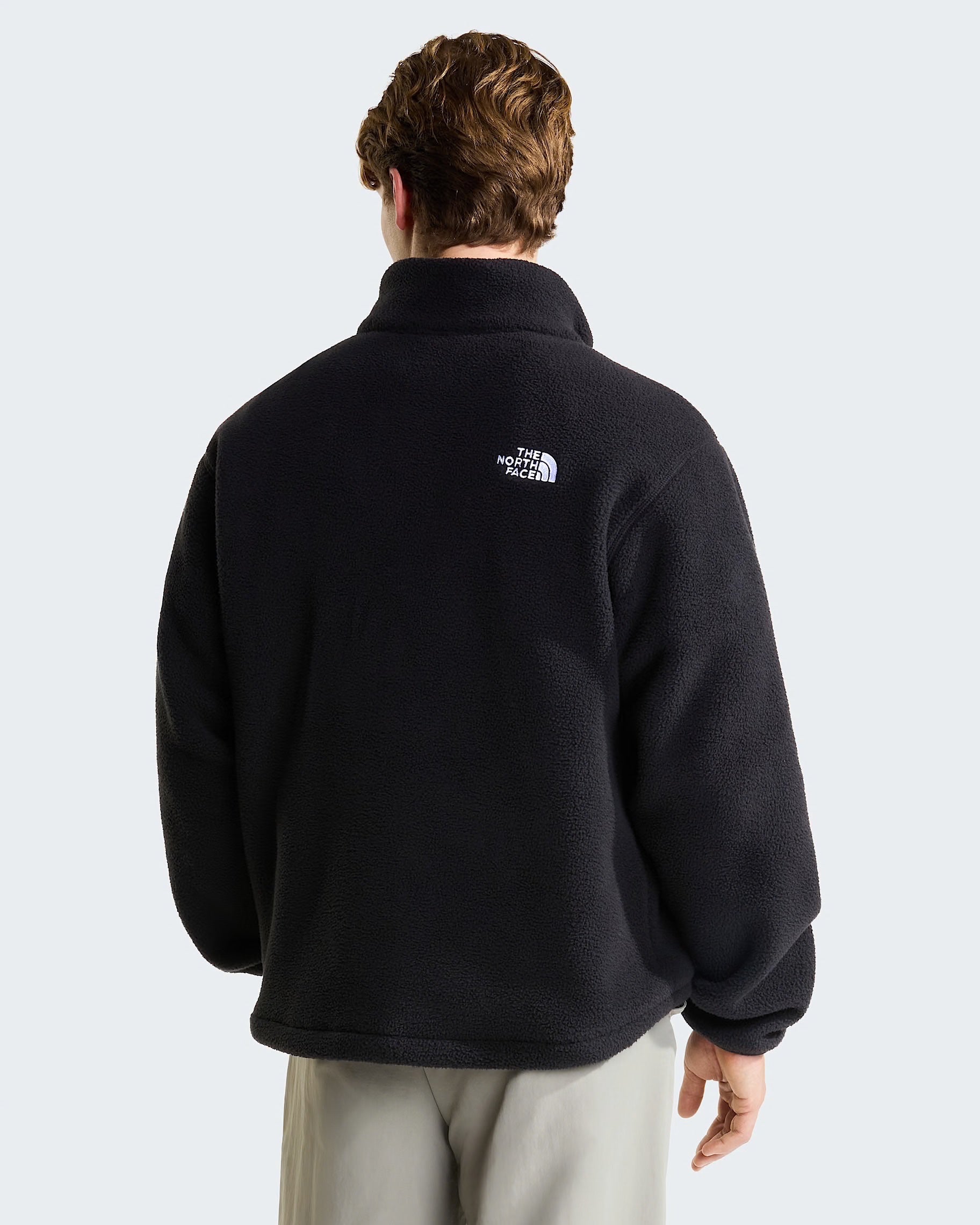 Vista posteriore di un uomo che indossa un pullover in pile nero Follower SRL con logo The North Face bianco