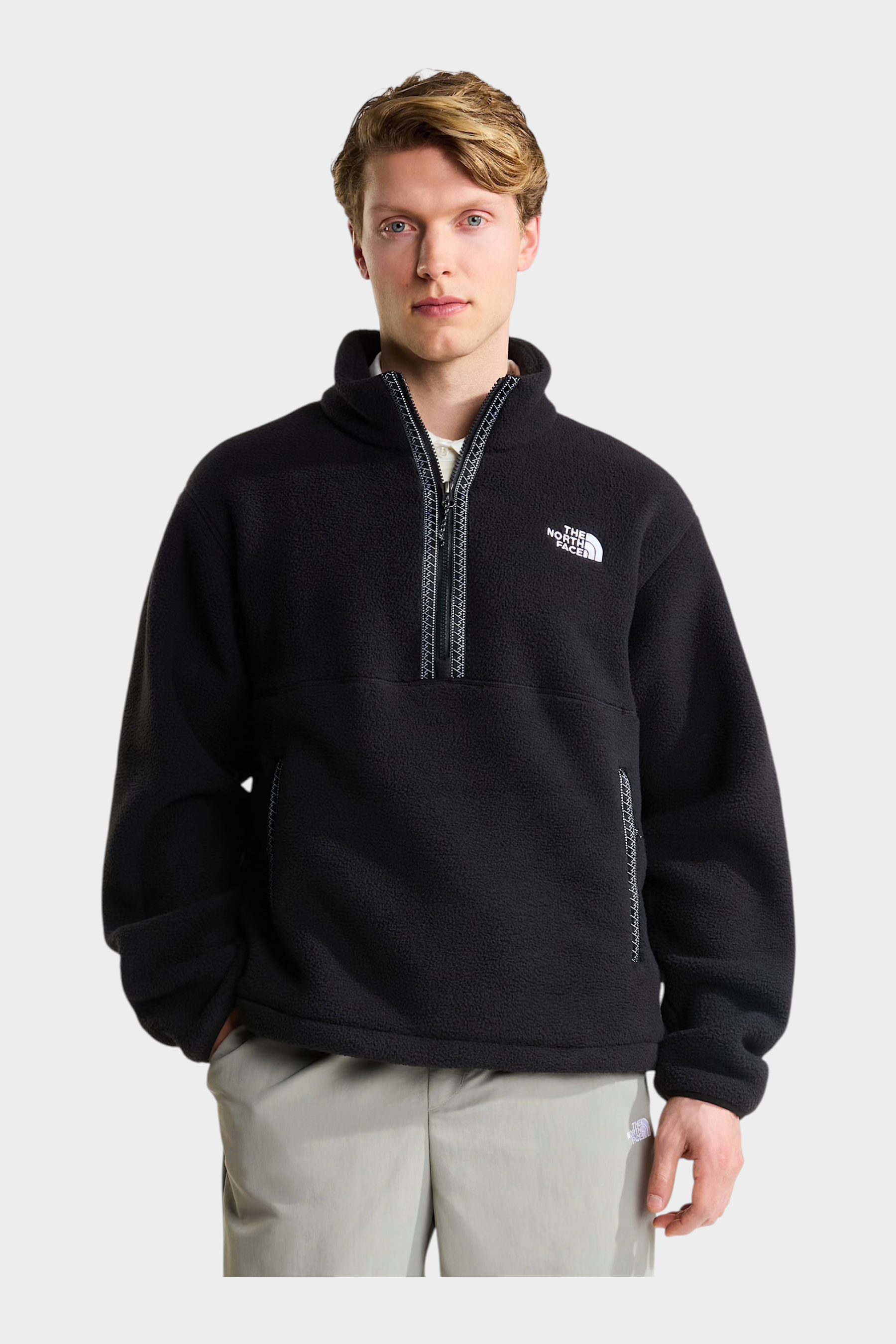 Modello indossa un pullover in pile nero Follower SRL con cerniera a un quarto e logo The North Face sul petto