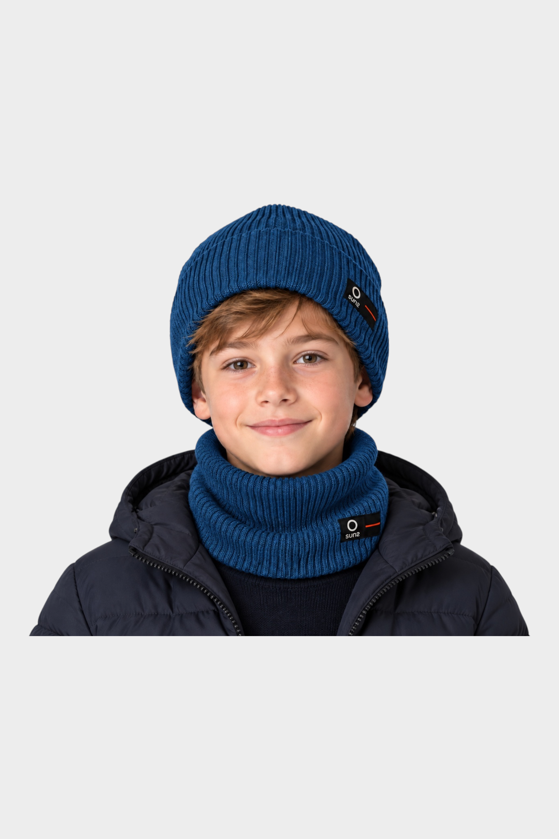 Ragazzo indossa berretto e scaldacollo blu a costine Follower SRL con logo SUNS su giacca scura