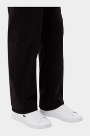 Sneakers bianche in pelle LACOSTE Carnaby indossate con pantaloni scuri, vendute da Follower SRL