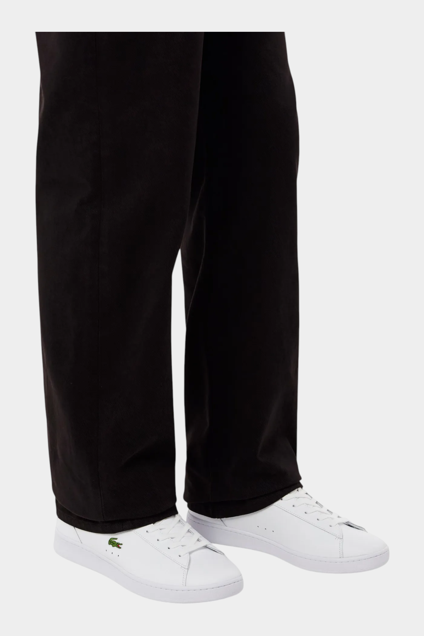 Sneakers bianche in pelle LACOSTE Carnaby indossate con pantaloni scuri, vendute da Follower SRL